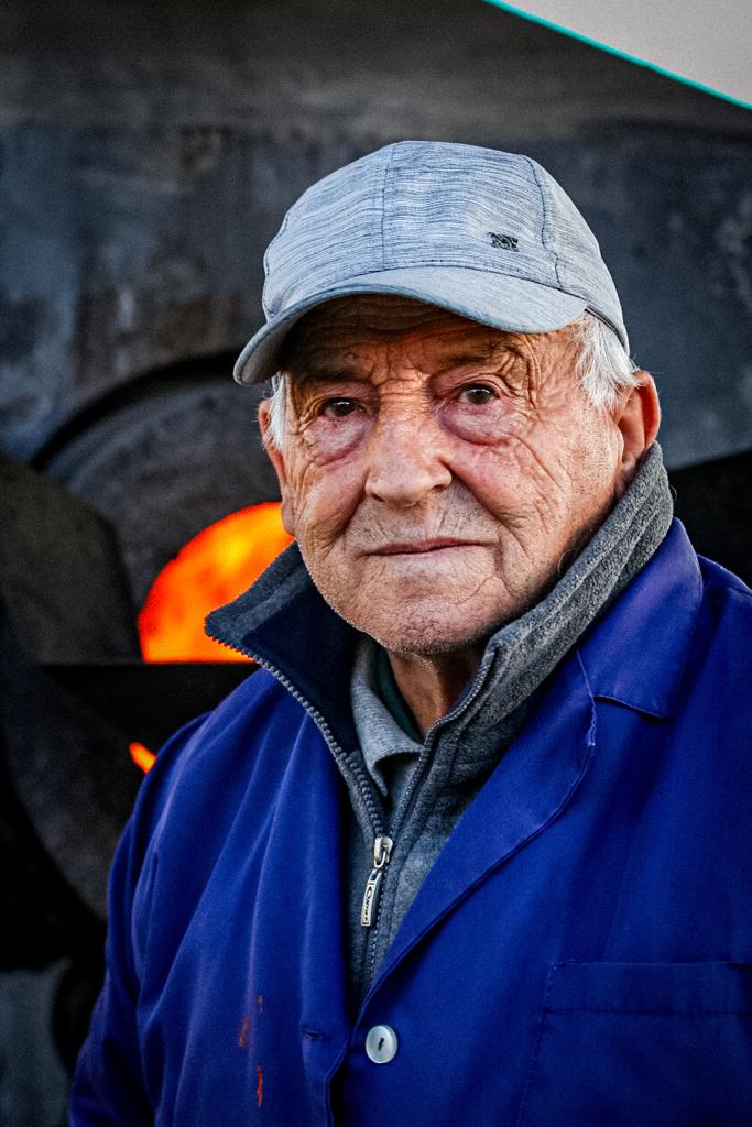 Señor con gorra y horno de leña pimientos